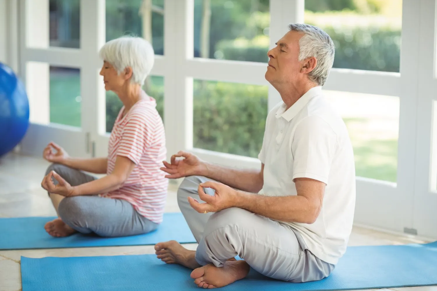 senior couple performing yoga exercise on mats