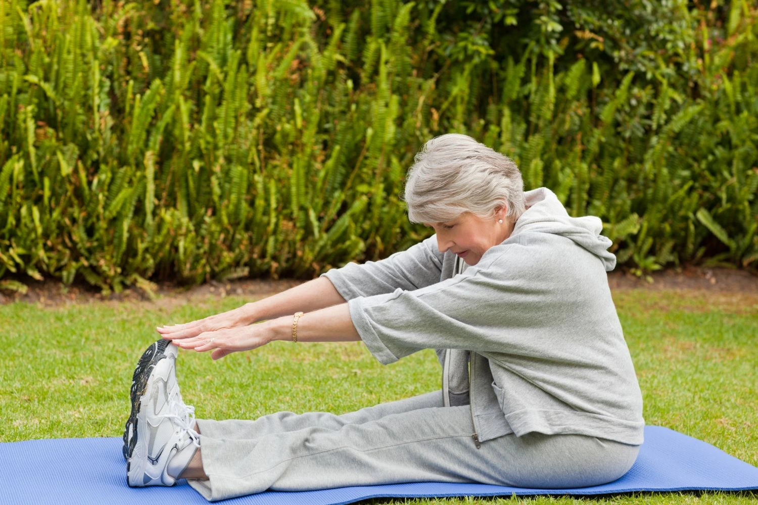 Senior woman doing stretching exercise in garden