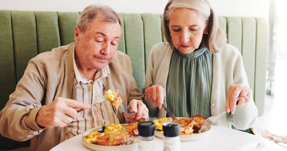 Senior couple eating breakfast, highlighting foods seniors should avoid